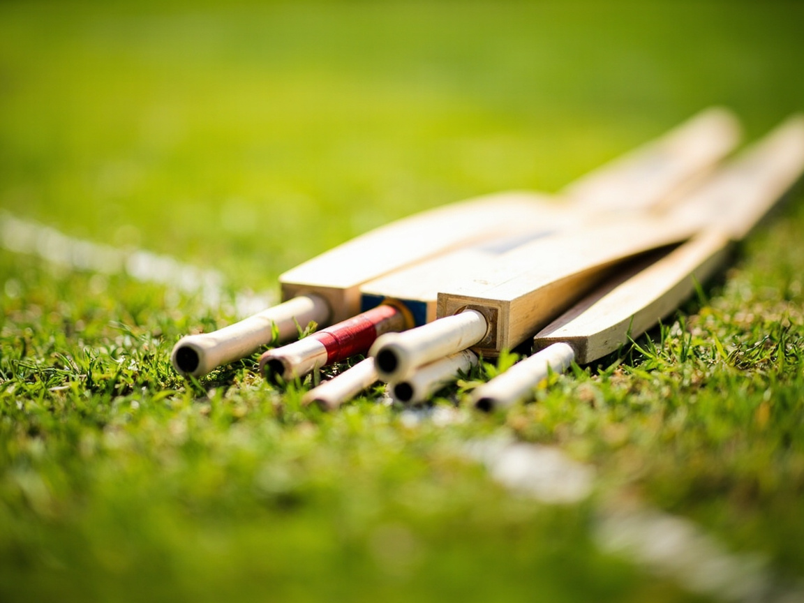 Cricket players in coloured jerseys walking out across a sunny ground before a daytime match